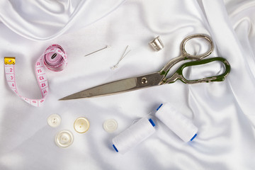 Sewing accessories on white satin fabric.