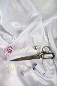 Sewing accessories on white satin fabric.