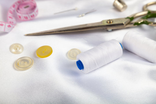 Sewing accessories on white satin fabric.
