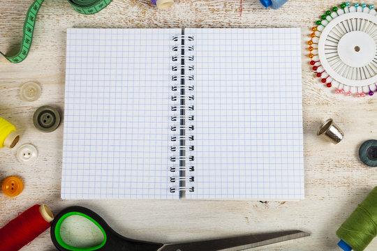 Sewing accessories and an open notebook