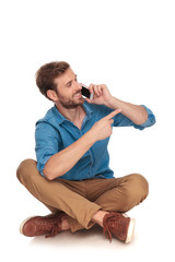 seated  man talking on the phone points finger to side