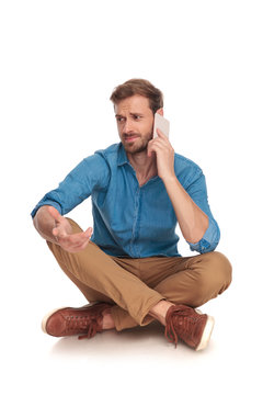 seated man is having a confusing discussion on the phone