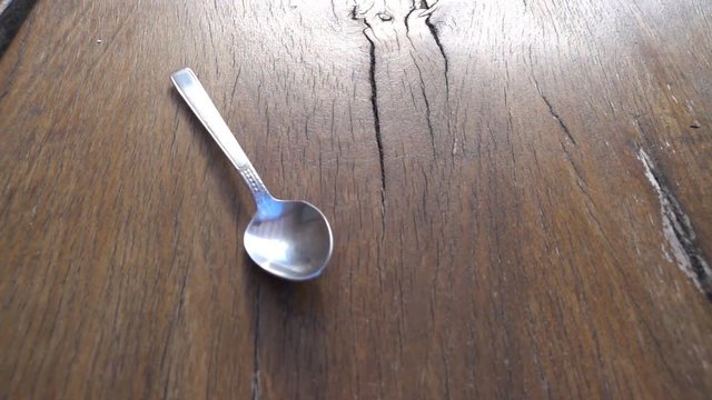 Slow motion of spoon falling on wooden table