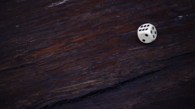 Slow motion of dice falling on wooden table