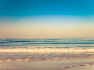 Fototapeta na wymiar motion blurred gentle waves splashing in the morning on the sand beach