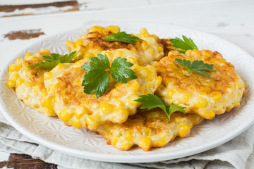 Cutlets from grains of canned corn with parsley on a plate. Wooden background.
