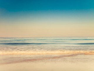 Fototapeta na wymiar motion blurred gentle waves splashing in the morning on the sand beach