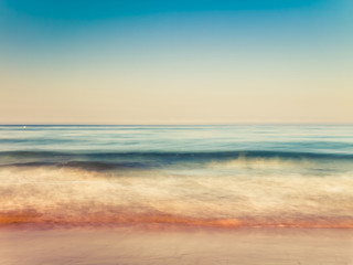 motion blurred gentle waves splashing in the morning on the sand beach