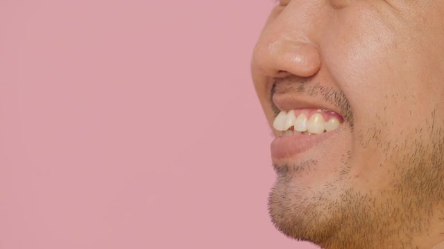 Close up mouth of a laughing young asian man on pink background.