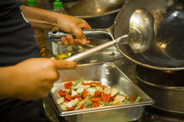Hands of cook preparing roast with salad