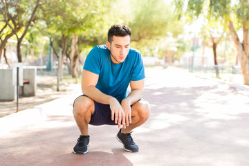 Determined Runner Crouching On Track After Workout In Park