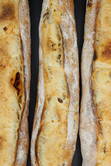Three fresh French baguettes on dark background