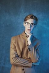 Studio portrait of young male model with red hair and freckles. Weared in brown coat and glasses....