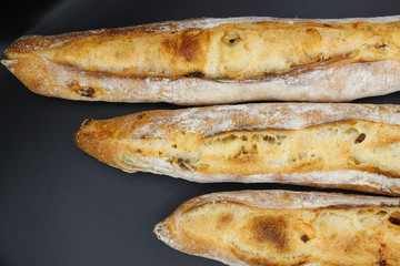 Three fresh French baguettes on dark background