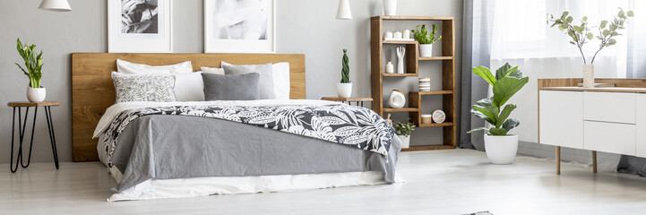 Scandinavian style, wooden furniture in a stylish, monochromatic bedroom interior with plants, gray...