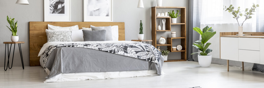 Scandinavian style, wooden furniture in a stylish, monochromatic bedroom interior with plants, gray walls and industrial elements