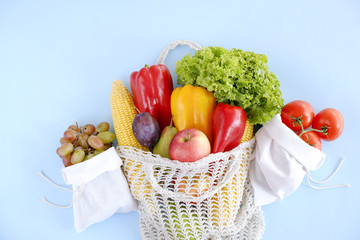 Bunch of mixed organic fruit, vegetables & greens: corn cob, tomato, pepper, lettuce salad leaf, pear, plum and apples in reusable cotton net bag. Zero waste concept. Background, copy space, close up.