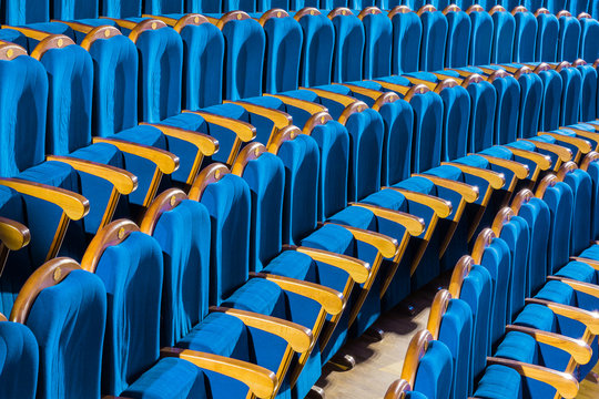 Blue plush chairs with wooden armrests in the auditorium. Empty auditorium in the theater.