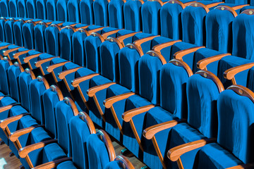 Blue plush chairs with wooden armrests in the auditorium. Empty auditorium in the theater.