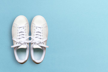 White sneakers isolated on blue background. Top view and copy space. Health concept