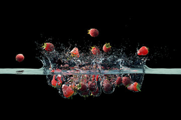 strawberries and raspberry falling into water