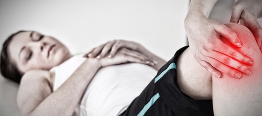 Composite image of masseuse massing the knee 