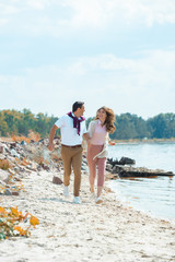 happy couple holding hands while running on sandy beach