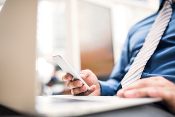 Fototapeta premium A young businessman with laptop and smartphone, working.