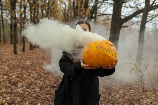 Girl carrying smoky pumpkin in forest