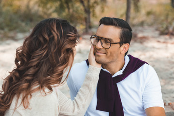 side view of romantic couple looking at each other on sandy beach