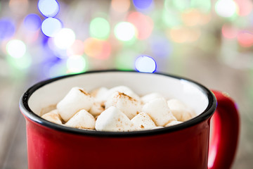 Christmas cocoa with marshmallow and Christmas lights background on wooden table

