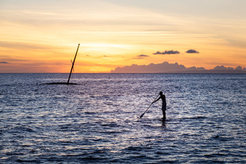 Sunset Silhouette of a Man on a Paddleboard Near an Old Shipwrecked Sailboat in Lahaina, Maui, Hawaii with Copy Space