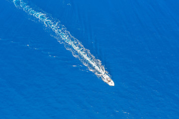 Luftaufnahme eines Motorbootes welches über türkis blaues Meer fährt