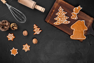 Fototapeta na wymiar Christmas homemade gingerbread cookies, spices and cutting board on dark background with copy space for text top view. New year and christmas postcard
