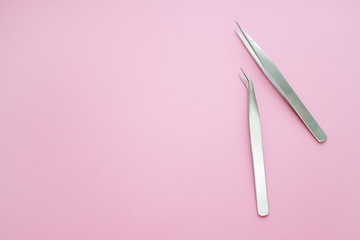 tools for Eyelash Extension Procedure. Two tweezers on pink background. copyspace mockup - Beauty and fashion concept