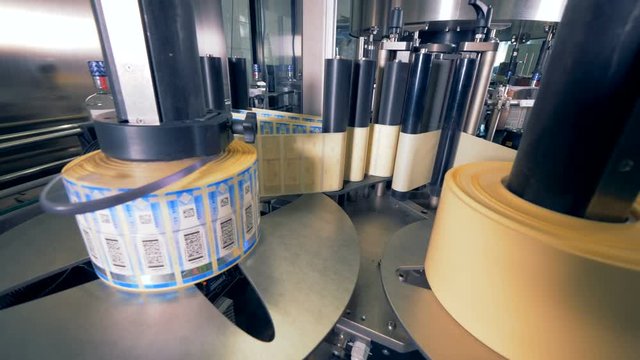 Rolls of tags for bottles. Special machine spins, putting tags on bottles at a plant.