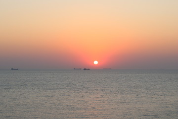 Sunset with container ships waiting on their turn to cross through Gallipoli seen from the island Bozcaada in Turkey.