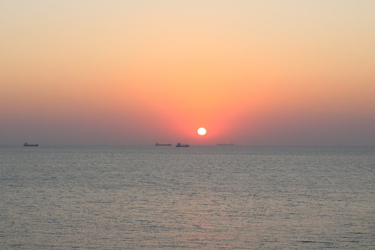 Sunset with container ships waiting on their turn to cross through Gallipoli seen from the island Bozcaada in Turkey.