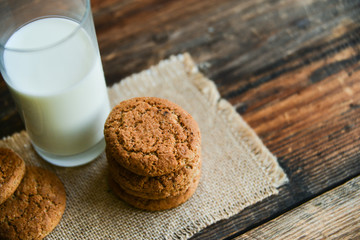 fresh oatmeal cookies and milk on wooden background with spikes of oats
