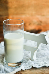 glass of milk, cow on natural wooden background in rustic style, rural style, concept of natural products and farming