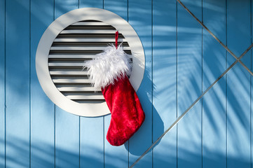 Stocking hanging against a seaside and nautical background of blue wood with palm frond shadows. © lazyllama