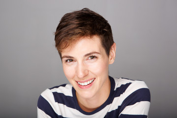 Close up attractive young woman with short hair smiling against gray background