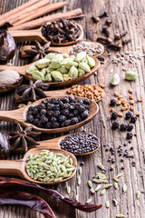 Different types of whole Indian spices in wooden background close-up.