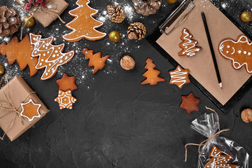 A Christmas gingerbread cookie in the shape of a Christmas tree in a cellophane packing on the background of a dark table. Christmas gift concept.