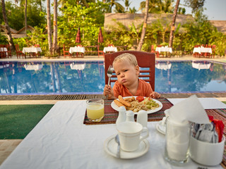 Cute boy picky eater frustrating over the dish with sausages, vegetables, spaghetti served with...