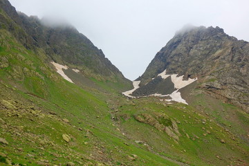 Fototapeta na wymiar Hiking trail crossing a snowy Tobavarchkhili mountain pass in Caucasus Mountains in Georgia on a hike to Silver Lakes