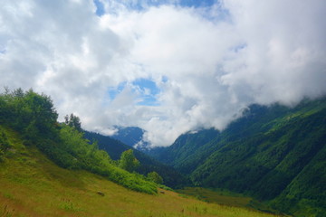 Hiking trail to Silver lakes with clouds around the mountains going via Tobavarchkhili from Mukhuri to Khaishi in Caucasus mountains, Georgia