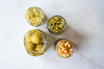 Jars of Pickled Vegetables Green and White Asparagus, Artichoke Heart and Unripe Green Almond Pickles in Glass Bottle.