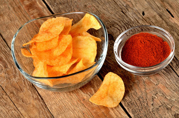 Hot pepper potato crisps - chips and pepper powder on wooden table