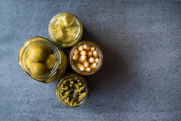 Jars of Pickled Vegetables Green and White Asparagus, Artichoke Heart and Unripe Green Almond Pickles in Glass Bottle.